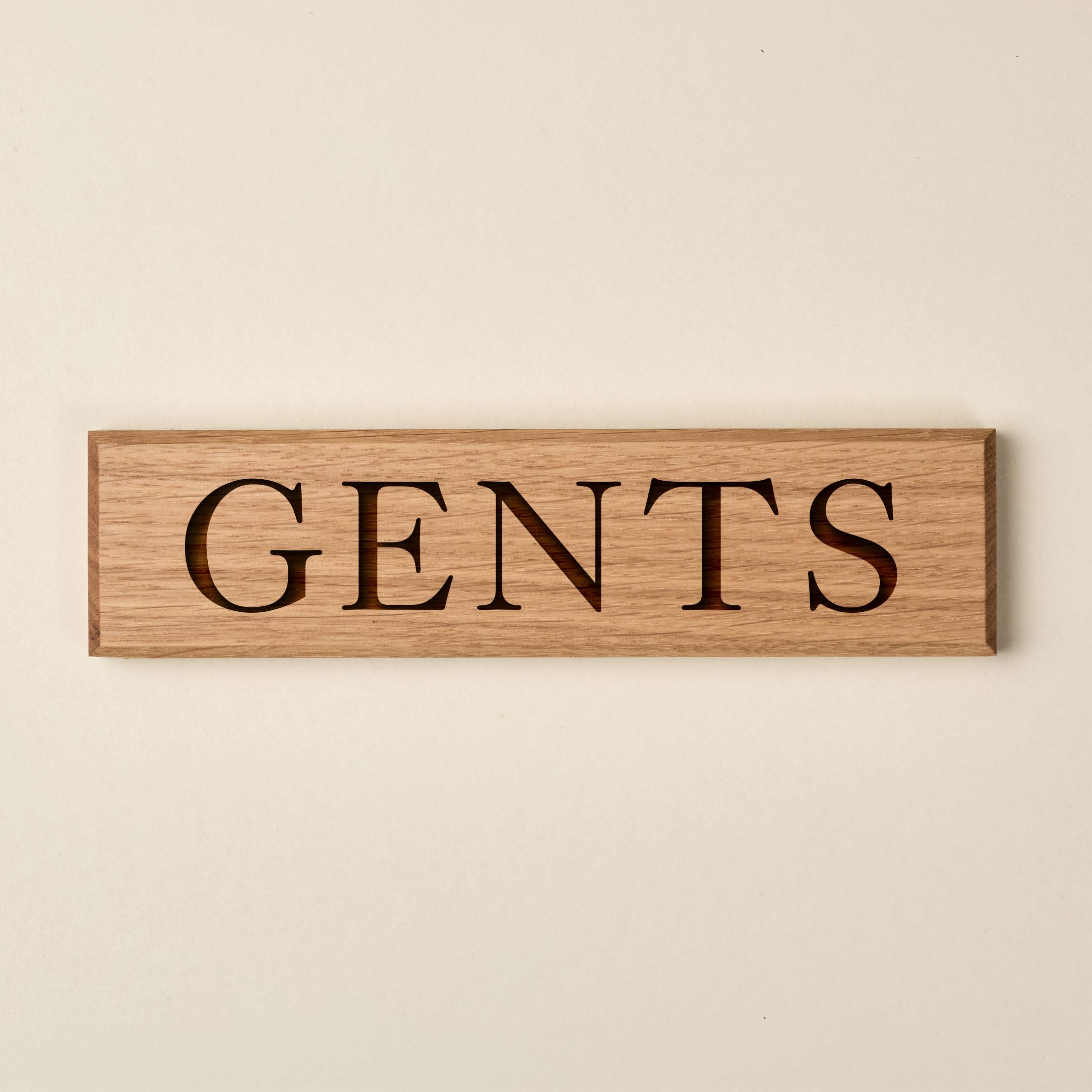 Horizontal oak "GENTS" door sign featuring engraved serif lettering. The sign showcases a warm, natural wood finish with a visible grain and dark recessed text.
