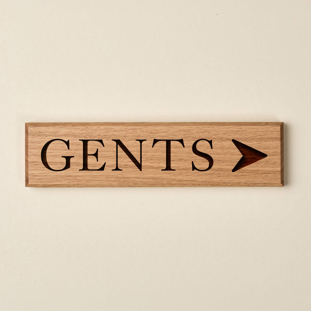 Slimline oak "GENTS" directional sign featuring engraved serif lettering and a right-pointing arrow. The natural wood finish has a visible horizontal grain and dark recessed text.