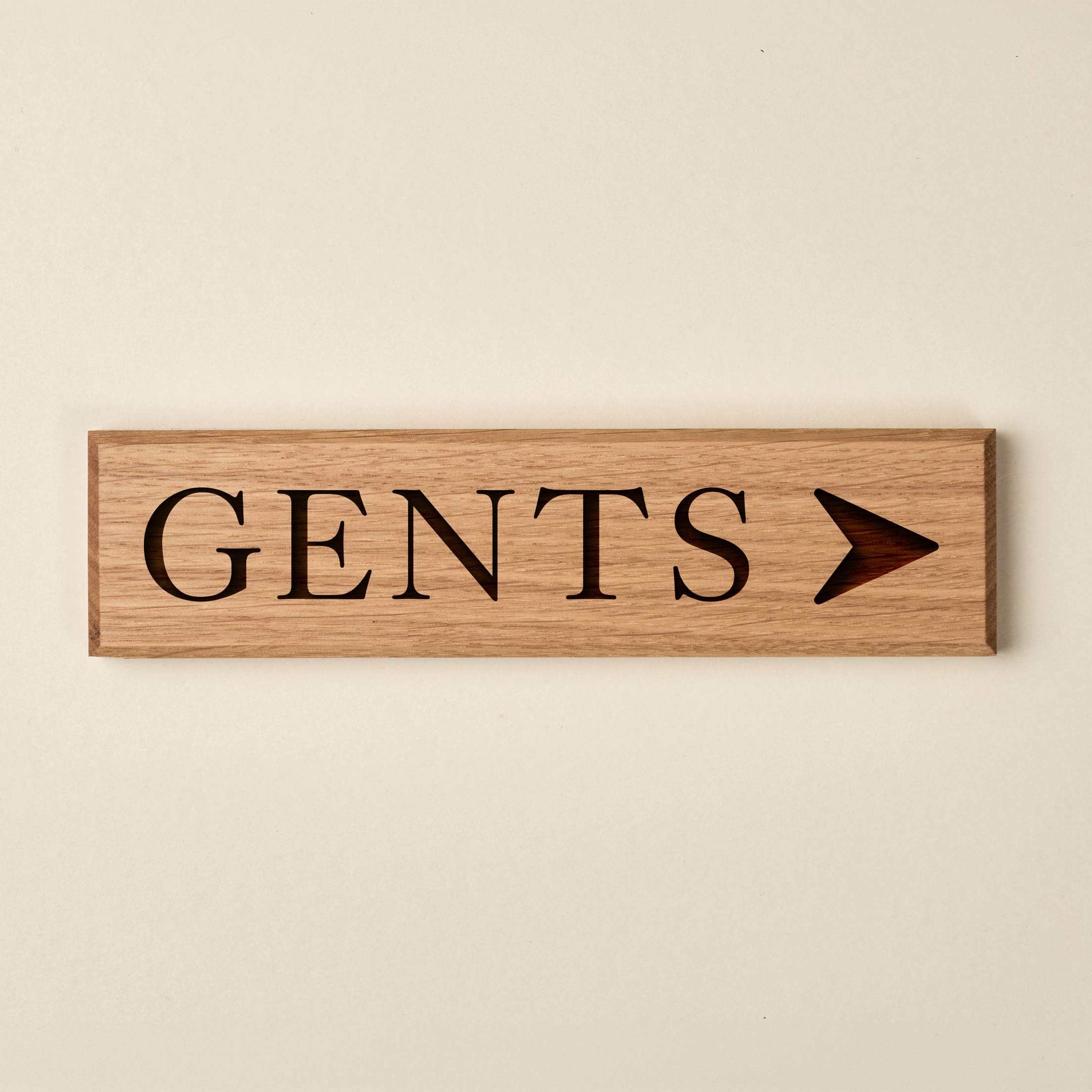 Slimline oak "GENTS" directional sign featuring engraved serif lettering and a right-pointing arrow. The natural wood finish has a visible horizontal grain and dark recessed text.