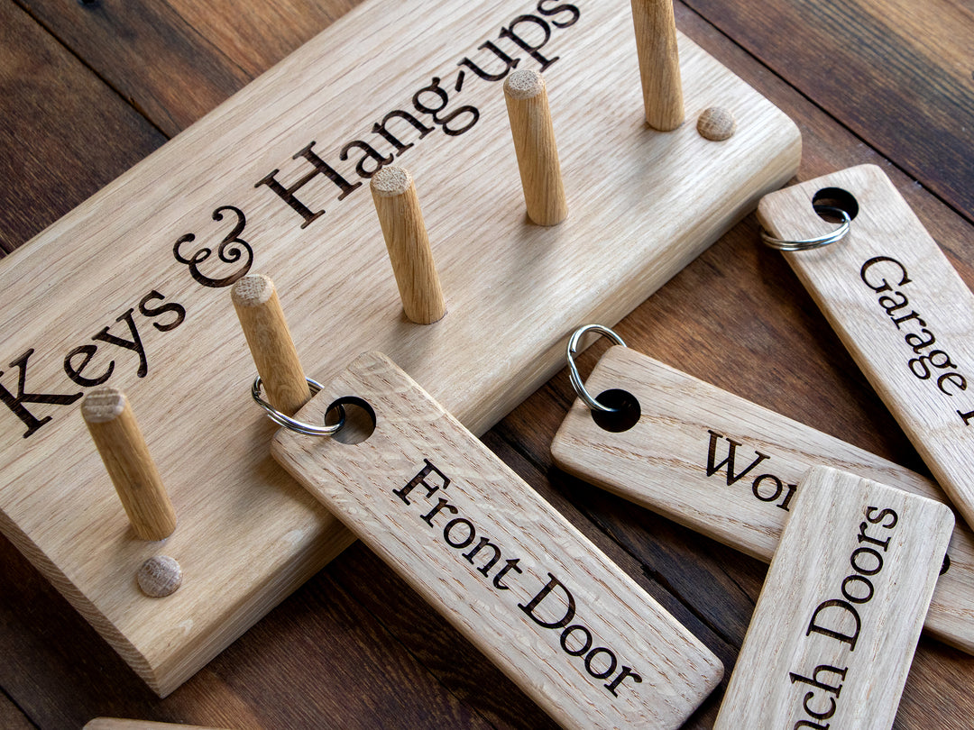Personalised Oak Key Rack, engraved with Keys & Hangups with engraved Oak Keyrings lying flat on wood boards