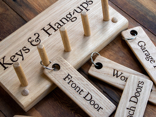 Personalised Oak Key Rack, engraved with Keys & Hangups with engraved Oak Keyrings lying flat on wood boards