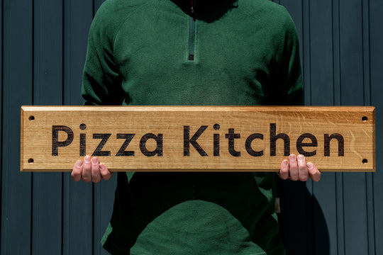 Oak Sign engraved with Pizza Kitchen, held in two hands upright. 