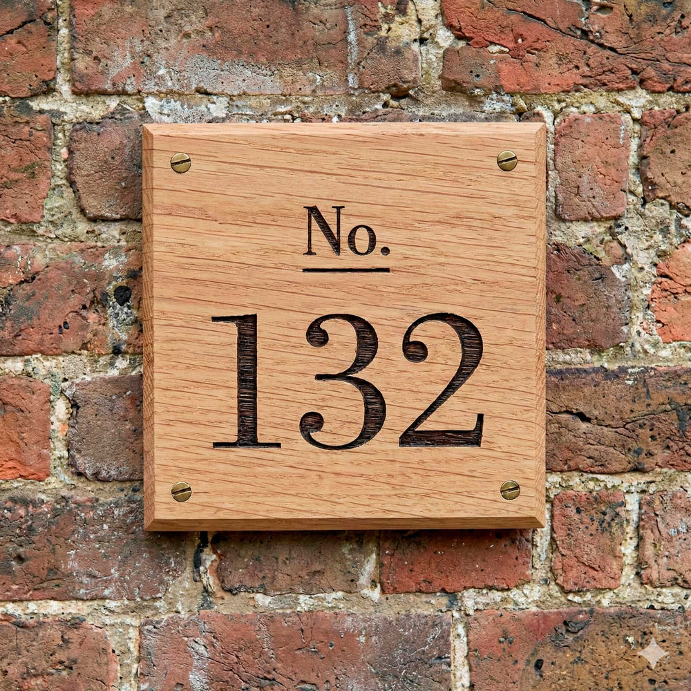 Close-up of the wooden house number sign engraved No 132 highlighting the engraving detail, bevelled edges, brass screw fixings and solid Oak grain. 