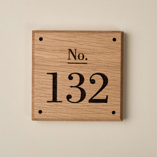 Wooden Victorian Oak House Number Sign in a front-facing studio view against a plain background, showing the engraved serif numbering '132', bevelled edge finish, screw holes and natural grain.