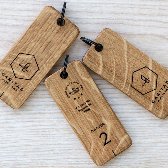 Three wooden keyrings with different engraved designs and text, laid out on a wooden surface.