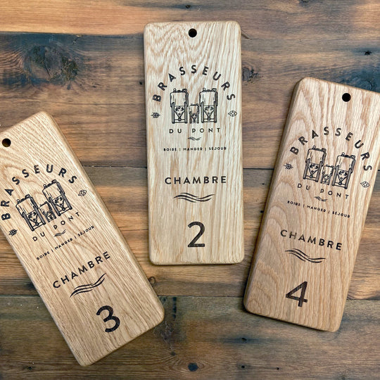 Three Hotel room signs with drill hole at top for hanging. Engraved with Brassuers du Pont Hotel Logo and the room names and numbers. 